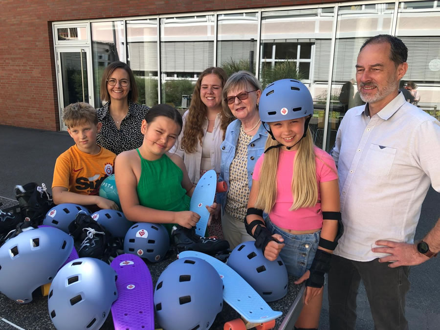 Lachende Kinder mit Helmen und Skatebords die sie als Geschenk erhalten haben